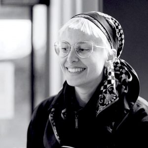 Auf dem Bild ist Olga zu sehen; sie ist in aufrechter Haltung und lächelt.